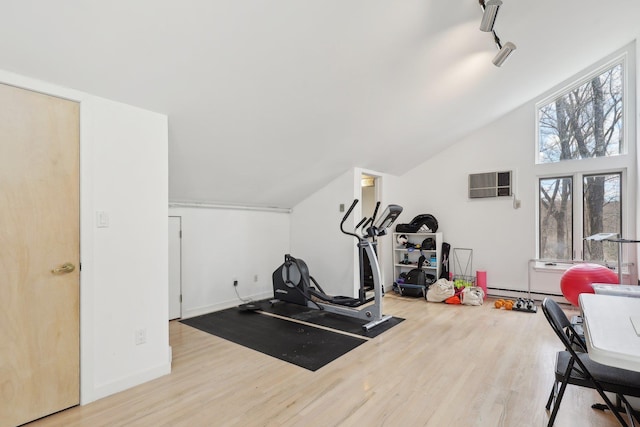 exercise area featuring track lighting, a wall mounted AC, lofted ceiling, and wood finished floors