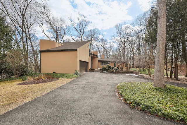 view of property exterior with aphalt driveway and an attached garage