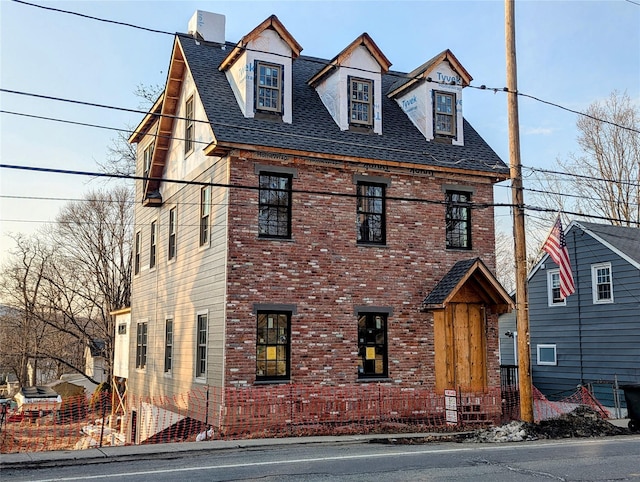 view of front of home featuring roof with shingles and brick siding