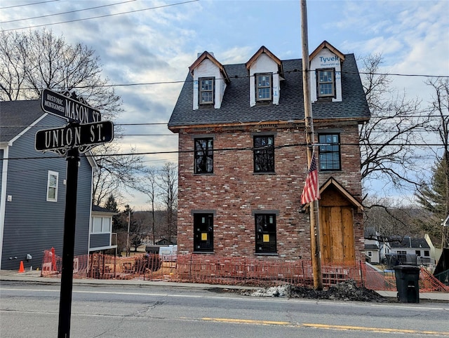 exterior space featuring a shingled roof and brick siding