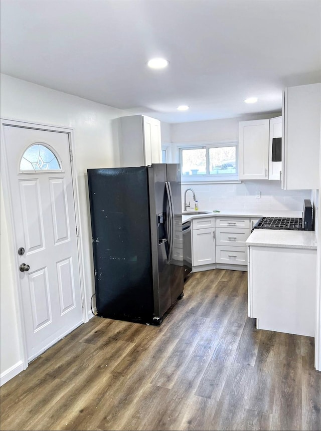 kitchen with appliances with stainless steel finishes, dark wood-type flooring, light countertops, white cabinetry, and a sink