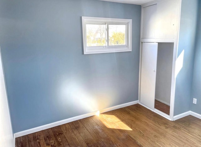 unfurnished bedroom featuring a closet, wood finished floors, and baseboards