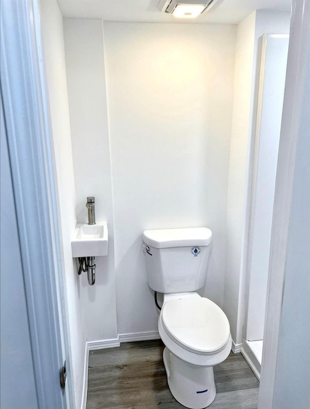 bathroom featuring toilet, baseboards, and wood finished floors