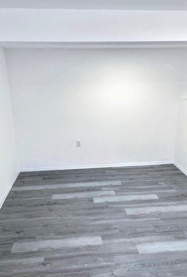 unfurnished room with baseboards and wood finished floors