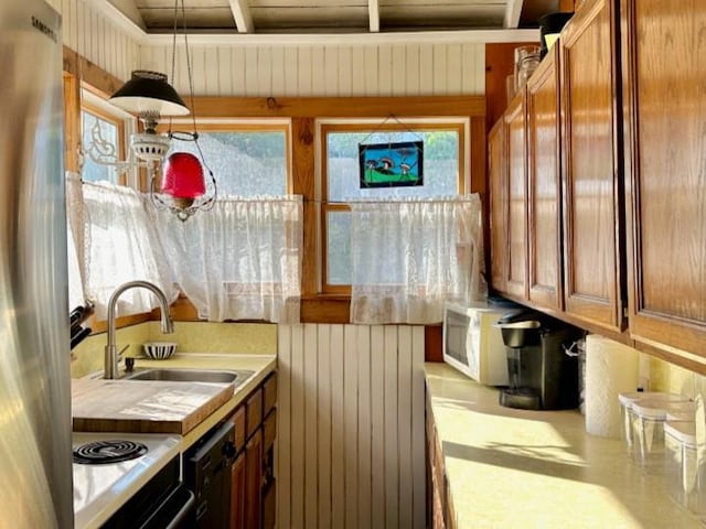 103 Greene Walk, Cherry Grove, NY 11782 - kitchen with light countertops, a sink, brown cabinetry, freestanding refrigerator, and wood walls