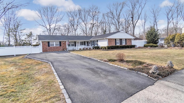 ranch-style house with brick siding, a front yard, fence, and aphalt driveway