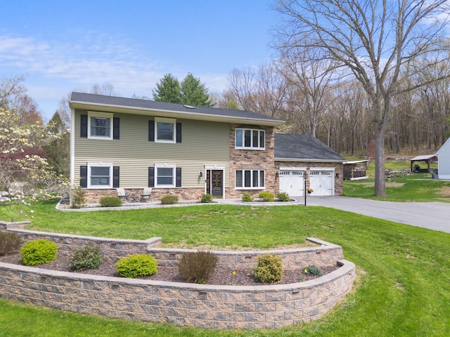 colonial inspired home featuring an attached garage, stone siding, driveway, and a front yard