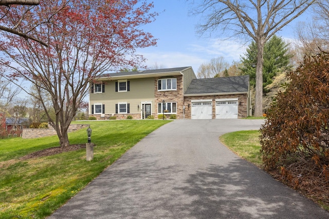 colonial home with an attached garage, a front yard, driveway, and stone siding