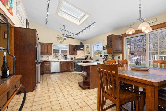 kitchen featuring open shelves, vaulted ceiling with skylight, light countertops, rail lighting, and stainless steel appliances