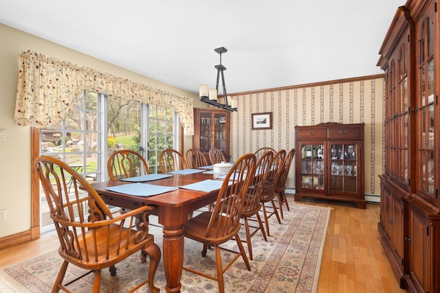 dining space featuring light wood-type flooring, baseboards, a baseboard heating unit, and wallpapered walls