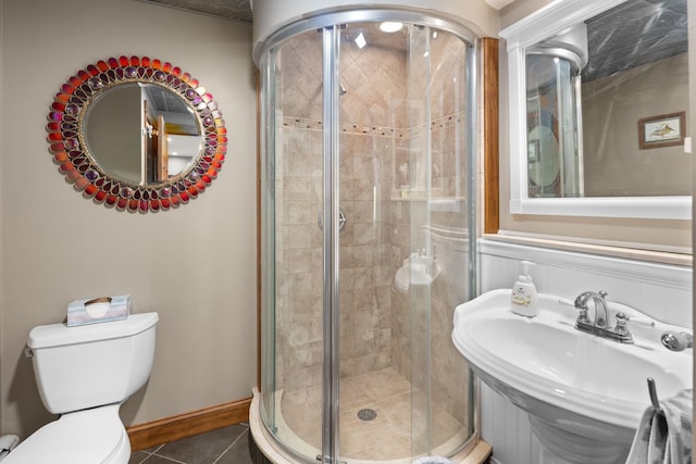 bathroom featuring tile patterned flooring, a sink, toilet, and a shower stall