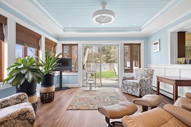 interior space featuring a baseboard radiator, a raised ceiling, wood finished floors, and ornamental molding