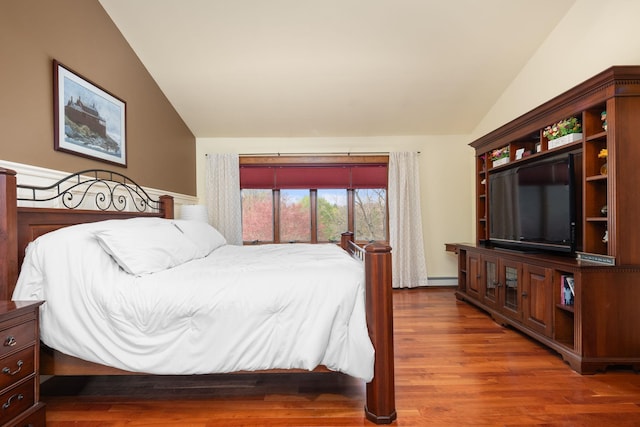 bedroom with wood finished floors, lofted ceiling, and baseboard heating