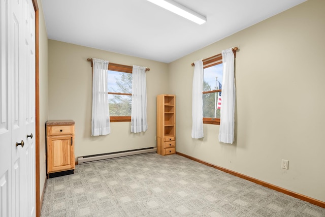 spare room featuring baseboards, a baseboard radiator, a healthy amount of sunlight, and light colored carpet