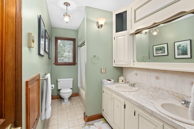 full bathroom with a sink, toilet, double vanity, tile patterned floors, and baseboards