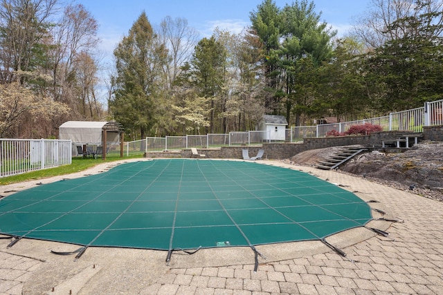 view of pool featuring an outdoor structure, a shed, a fenced in pool, and fence