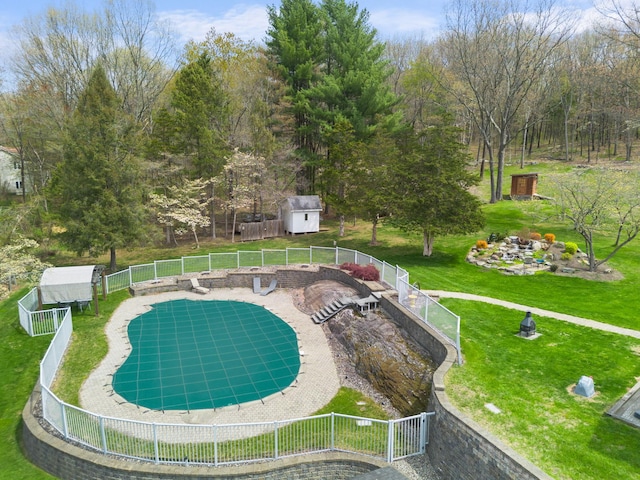 view of pool with a yard, a shed, an outbuilding, and fence