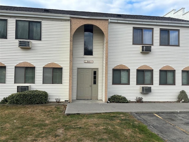 view of property featuring uncovered parking and a front lawn