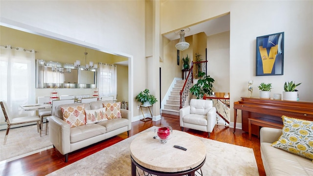 living room featuring a baseboard radiator, stairway, baseboards, and wood finished floors