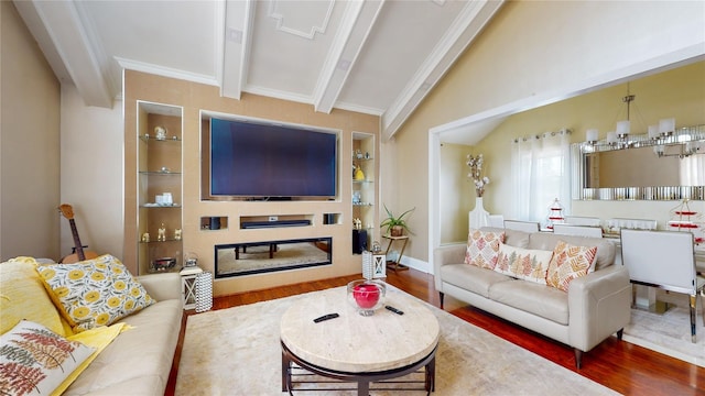 living area featuring vaulted ceiling with beams, wood finished floors, built in features, a glass covered fireplace, and crown molding