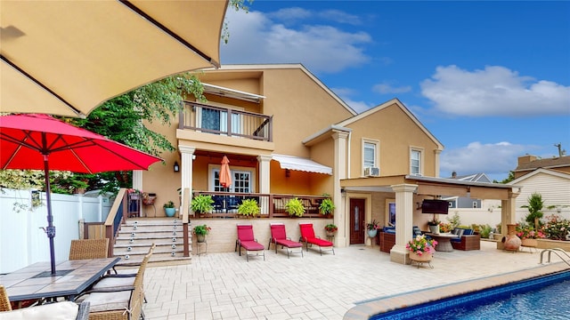 back of property featuring a patio, a balcony, an outdoor hangout area, fence, and stucco siding