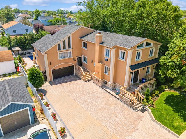 view of front of property featuring a chimney, an attached garage, fence, decorative driveway, and stucco siding