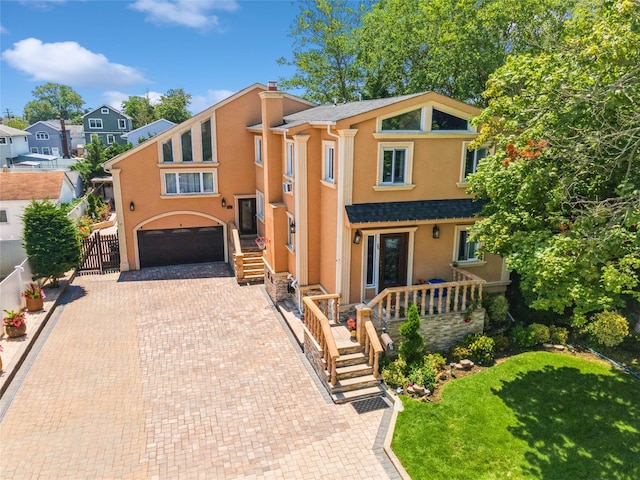 view of front of home with an attached garage, fence, decorative driveway, a front lawn, and stucco siding