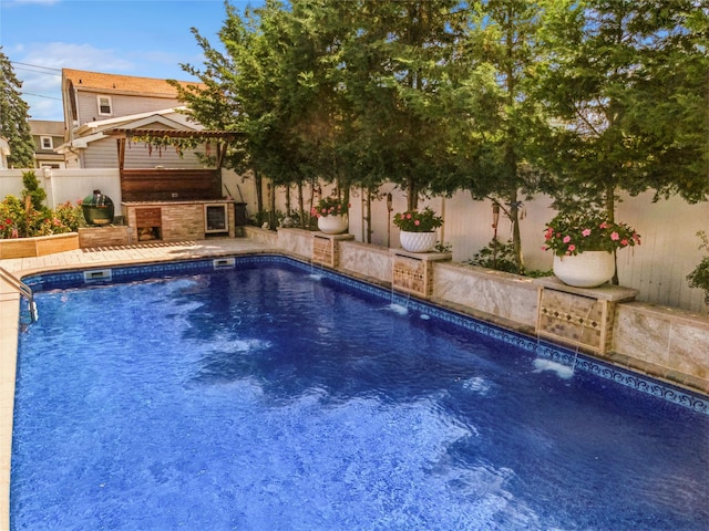 view of swimming pool featuring a patio area, an outdoor kitchen, a fenced backyard, and a fenced in pool