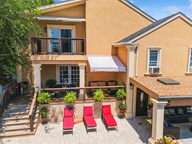 back of house with a balcony, a patio area, stucco siding, and french doors