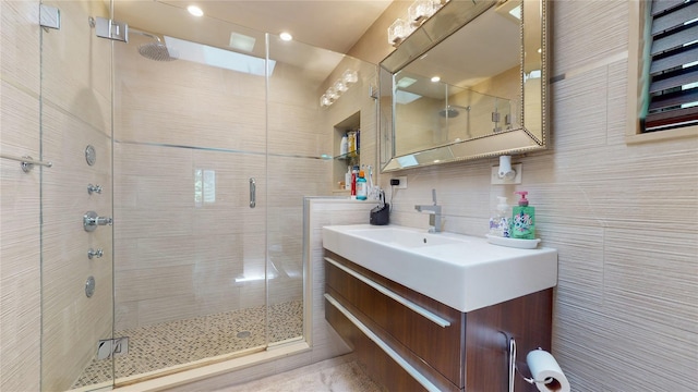 bathroom with tasteful backsplash, a stall shower, vanity, and tile walls