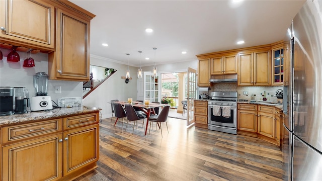 kitchen with light stone counters, dark wood finished floors, stainless steel appliances, decorative backsplash, and under cabinet range hood