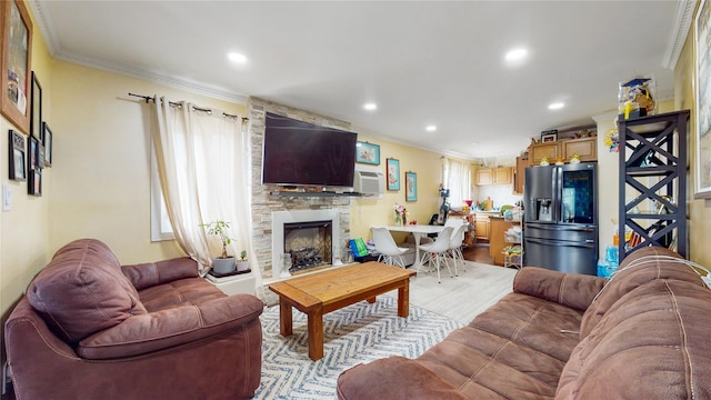 living room with recessed lighting, crown molding, and a stone fireplace