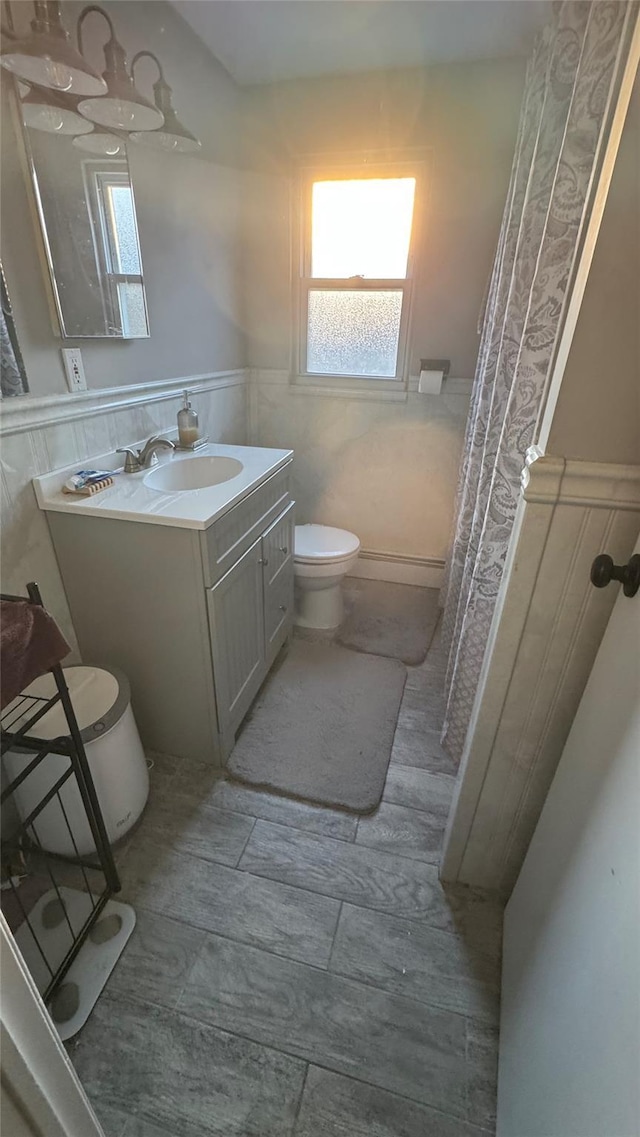 bathroom with wainscoting, vanity, and toilet