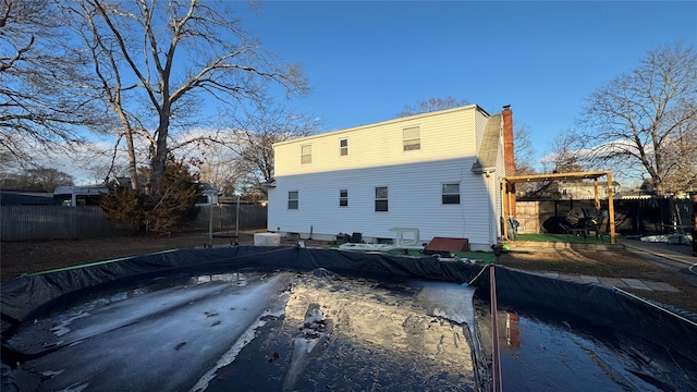 rear view of house with a chimney and fence