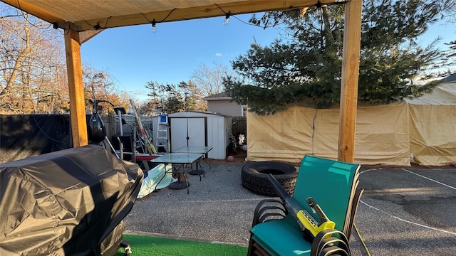 view of patio / terrace featuring a storage shed, a fenced backyard, grilling area, and an outbuilding