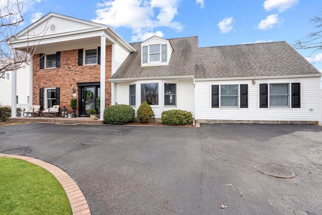 view of front of property with roof with shingles, driveway, and brick siding