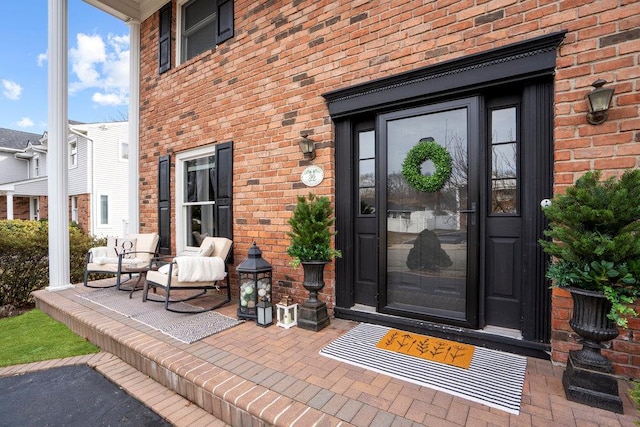 entrance to property featuring a porch and brick siding