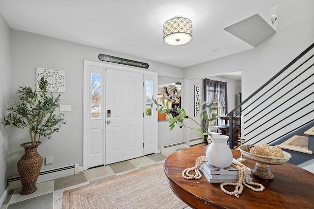 foyer entrance featuring a wealth of natural light, baseboard heating, and stairs