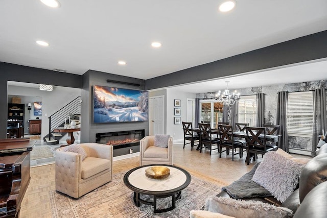 living area with baseboards, a glass covered fireplace, an inviting chandelier, stairs, and recessed lighting