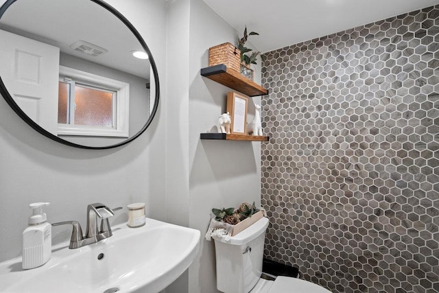 bathroom with toilet, curtained shower, a sink, and visible vents