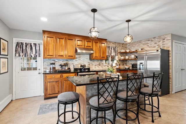 kitchen with appliances with stainless steel finishes, brown cabinets, under cabinet range hood, and baseboard heating