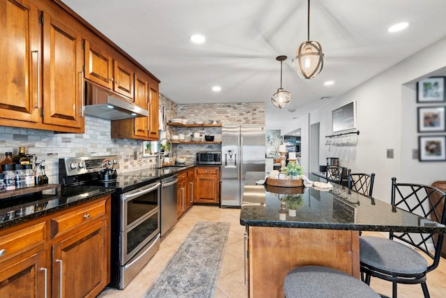 kitchen featuring stainless steel appliances, brown cabinetry, a sink, and under cabinet range hood