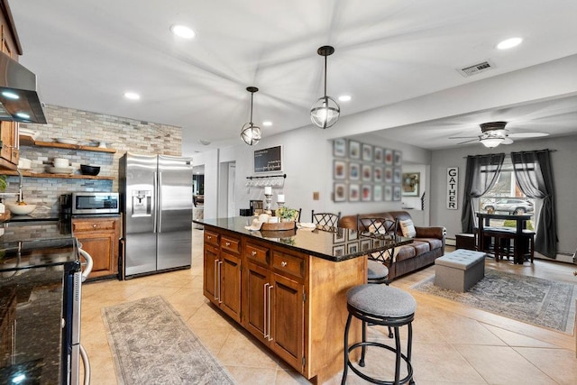 kitchen with light tile patterned floors, appliances with stainless steel finishes, a breakfast bar area, and visible vents