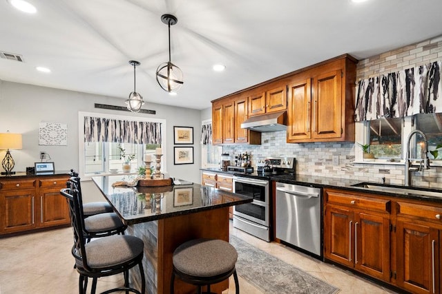 kitchen with tasteful backsplash, visible vents, appliances with stainless steel finishes, under cabinet range hood, and a sink