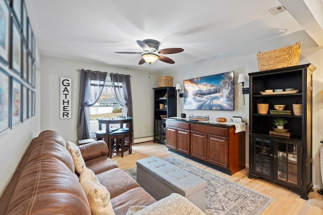 living area with light wood-style flooring, visible vents, baseboard heating, and a ceiling fan