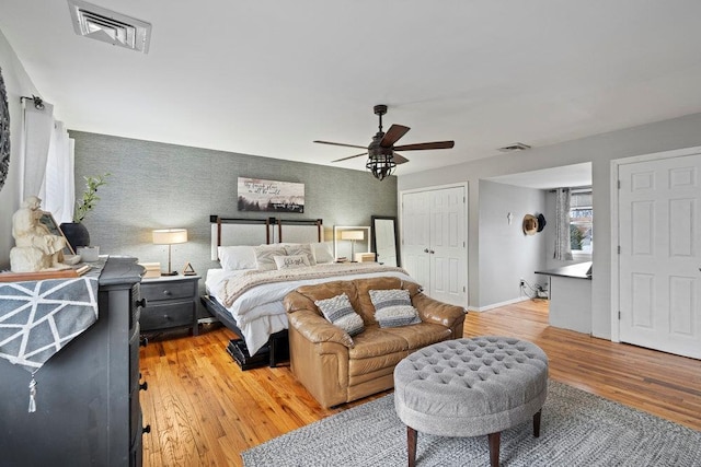 bedroom with light wood-type flooring, baseboards, visible vents, and ceiling fan