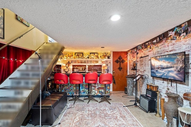 interior space featuring brick wall, a textured ceiling, and a dry bar