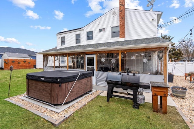 back of property with a patio, a fenced backyard, a sunroom, a yard, and a hot tub