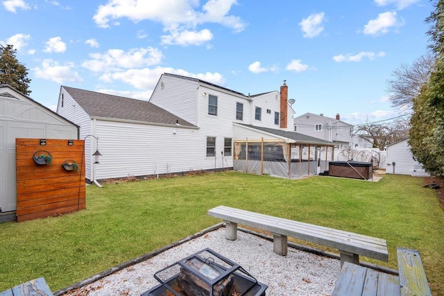 back of house with a lawn, a sunroom, and a hot tub