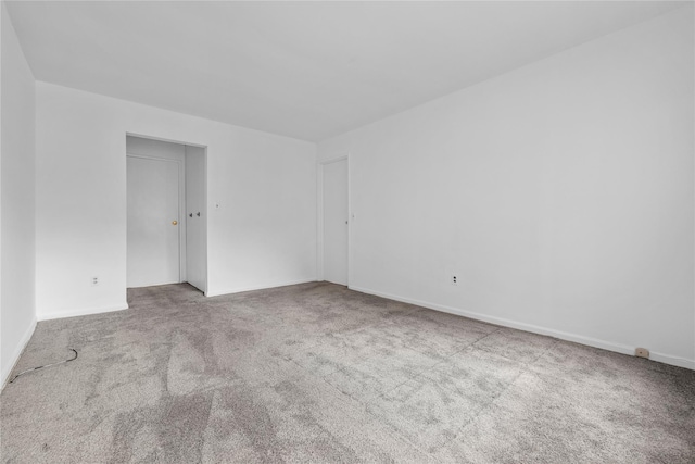 carpeted spare room featuring baseboards